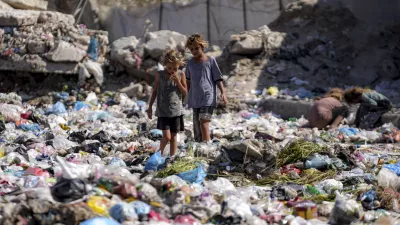 Displaced kids sort through trash at a street in Deir al-Balah, central Gaza Strip, Thursday, Aug. 29, 2024. (AP Photo/Abdel Kareem Hana)