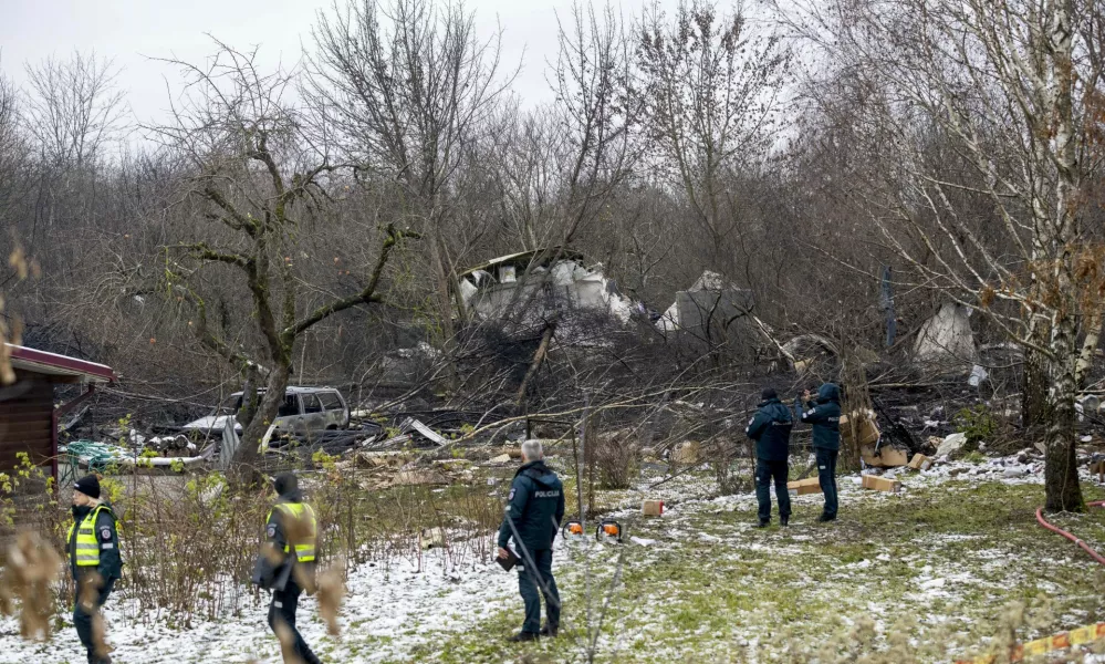 Lithuanian Emergency Ministry employees and police officers stand near the place where a DHL cargo plane crashed into a house near Vilnius, Lithuania, Monday, Nov. 25, 2024. (AP Photo/Mindaugas Kulbis)