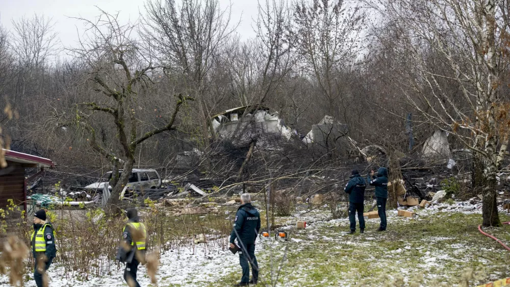 Lithuanian Emergency Ministry employees and police officers stand near the place where a DHL cargo plane crashed into a house near Vilnius, Lithuania, Monday, Nov. 25, 2024. (AP Photo/Mindaugas Kulbis)