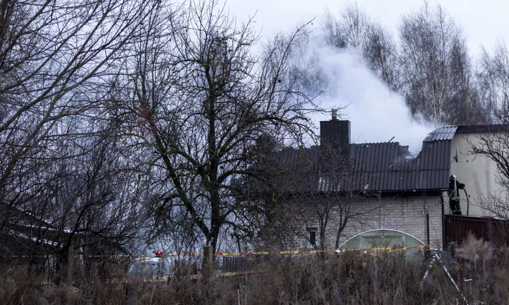 A smoke rises from the site where a DHL cargo plane crashed into a house near Vilnius, Lithuania, Monday, Nov. 25, 2024. (AP Photo/Mindaugas Kulbis)