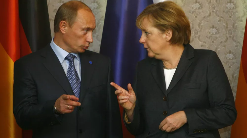 Russian President Vladimir Putin chats with German Chancellor Angela Merkel during the German-Russian governmental consultations St. Petersburg Dialogue in Wiesbaden October 15, 2007. REUTERS/Alex Grimm (GERMANY)