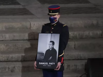 FILE - A Republican Guard holds a portrait of Samuel Paty in the courtyard of the Sorbonne university during a national memorial event, Wednesday, Oct. 21, 2020 in Paris. (AP Photo/Francois Mori, Pool, File)