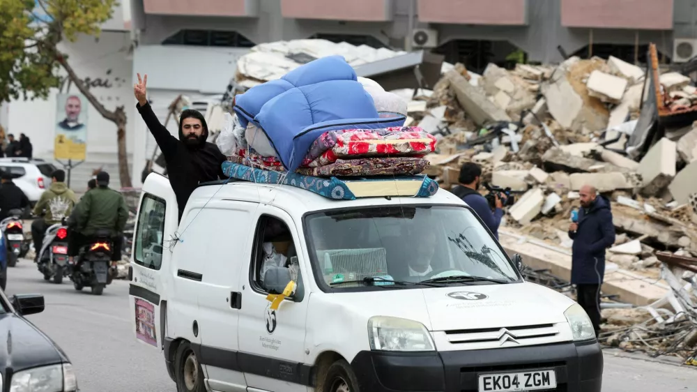 Moški pozdravlja iz natovorjenega avta na jugu Libanona, kjer se ljudje poskušajo vrniti na svoje domove. Foto: Reuters