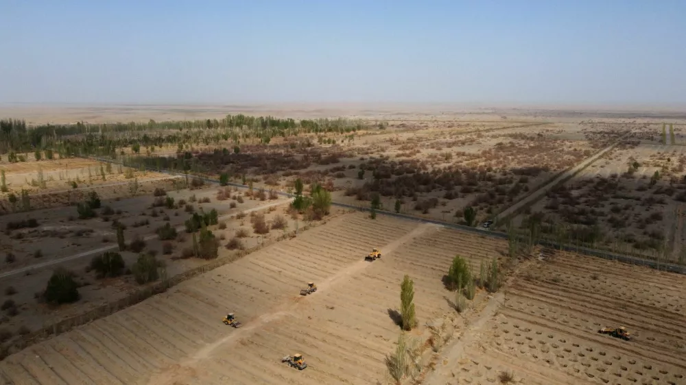 FILE PHOTO: Wheel loaders move soil to prepare a field for tree planting, at one of the sections of the Yangguan state-backed forest farm, on the edge of the Gobi desert, on the outskirts of Dunhuang, Gansu province, China, April 13, 2021. REUTERS/Carlos Garcia Rawlins/File Photo