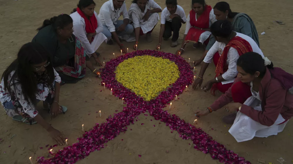 Members of a Non Government Organization(NGO) place candles around a symbol of 'red ribbon', the universal symbol of awareness and support for those living with HIV, on the eve of World AIDS Day, in Ahmedabad, India, Saturday, Nov. 30, 2024. (AP Photo/Ajit Solanki)