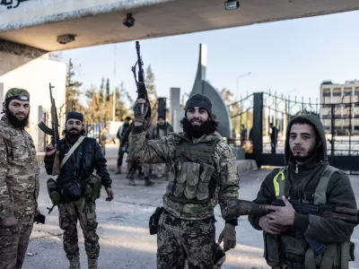 01 December 2024, Syria, Aleppo: Members of the Syrian armed opposition forces stand in front of the entrance to the Military College after taking control of it in the city of Aleppo. The Syrian government has lost control of the city of Aleppo, the country's second-largest, as opposition forces have made more territorial gains, a war monitor reported on Sunday. Photo: Anas Alkharboutli/dpa