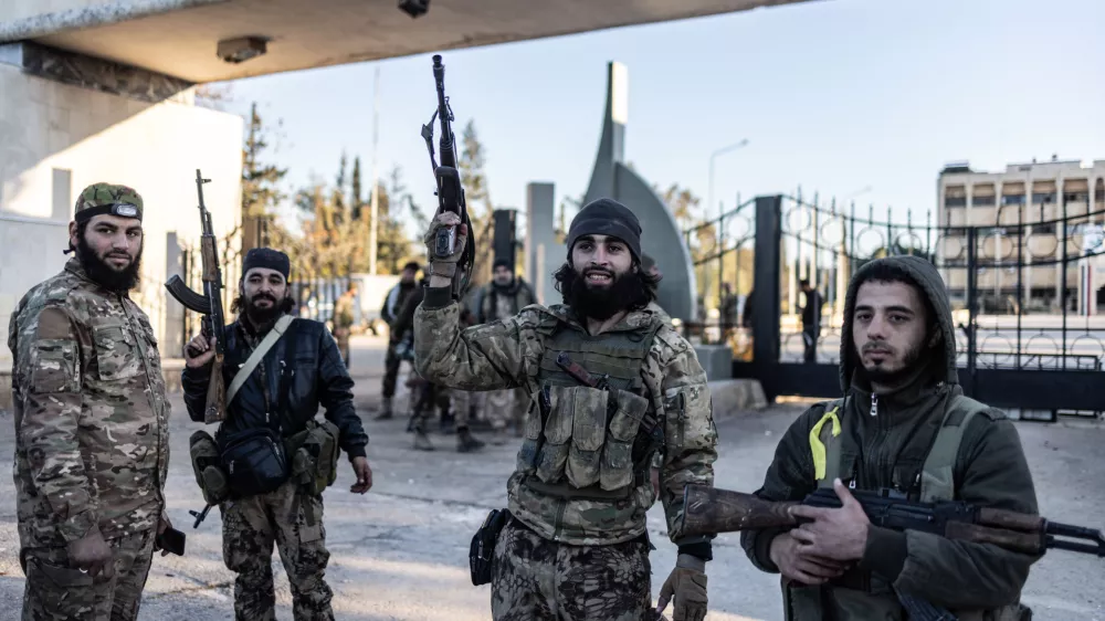 01 December 2024, Syria, Aleppo: Members of the Syrian armed opposition forces stand in front of the entrance to the Military College after taking control of it in the city of Aleppo. The Syrian government has lost control of the city of Aleppo, the country's second-largest, as opposition forces have made more territorial gains, a war monitor reported on Sunday. Photo: Anas Alkharboutli/dpa