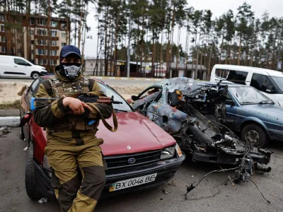 A member of the Ukrainian Territorial Defence Forces sits next to a destroyed car, amid Russia's attack on Ukraine, in Irpin, Kyiv region, Ukraine April 18, 2022. REUTERS/Zohra Bensemra