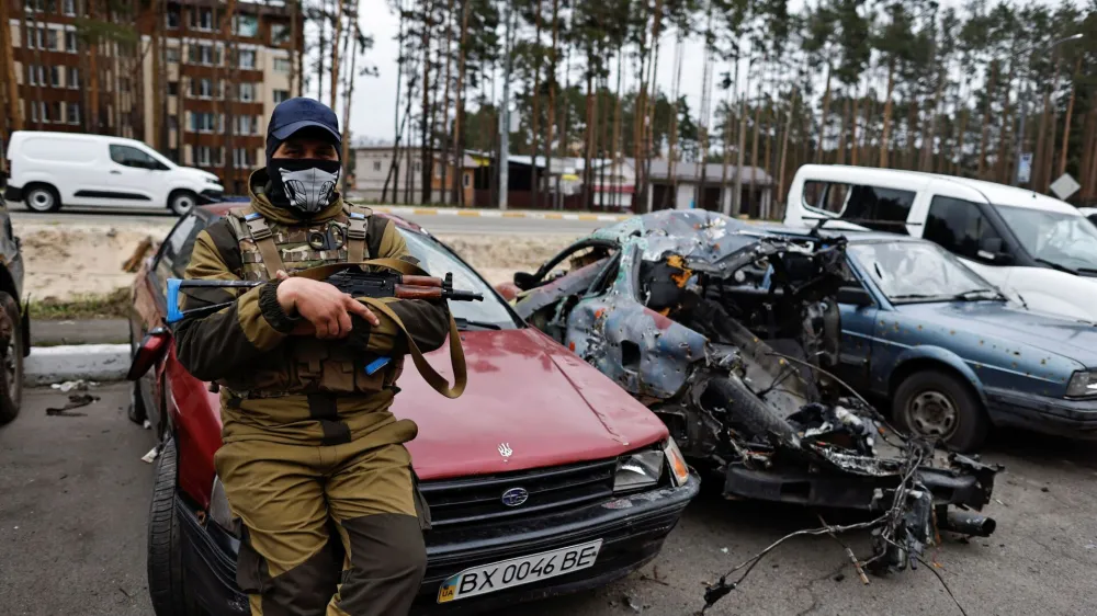 A member of the Ukrainian Territorial Defence Forces sits next to a destroyed car, amid Russia's attack on Ukraine, in Irpin, Kyiv region, Ukraine April 18, 2022. REUTERS/Zohra Bensemra