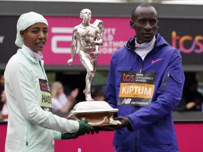 Women's race winner Sifan Hassan of the Netherlands and men's race winner Kelvin Kiptum of Kenya hold a trophy together after the London Marathon in London, Sunday, April 23, 2023.(AP Photo/Alberto Pezzali)