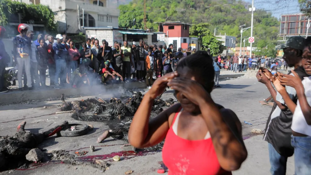 SENSITIVE MATERIAL. THIS IMAGE MAY OFFEND OR DISTURB People stand near the remains of alleged gang members after they were set on fire by a crowd of people, when trying to drive away, in Port-au-Prince, Haiti April 24, 2023. REUTERS/Ralph Tedy Erol