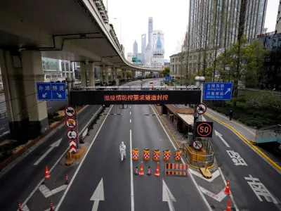 FILE PHOTO: A worker in a protective suit walks at an entrance to a tunnel leading to the Pudong area, after restrictions on highway traffic amid the lockdown to contain the spread of the coronavirus disease (COVID-19) in Shanghai, China March 28, 2022. REUTERS/Aly Song/File Photo