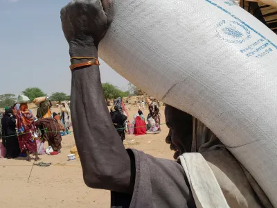 A worker of World Food Programme (WFP) carries a bag of relief grains to be distributed to Sudanese refugees who have fled the violence in their country, near the border between Sudan and Chad, in Koufroun, Chad April 28, 2023. REUTERS/Mahamat Ramadane