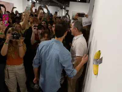 Art Basel visitors use their phones in front of a banana attached with duct-tape that replaces the artwork 'Comedian' by the artist Maurizio Cattelan, which was eaten by David Datuna, in Miami Beach, Florida, December 7, 2019. REUTERS/Eva Marie Uzcategui - RC2NQD93QLIJ