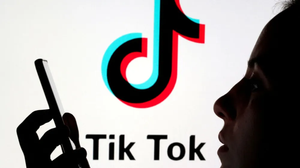 FILE PHOTO: A person holds a smartphone as Tik Tok logo is displayed behind in this picture illustration taken November 7, 2019. Picture taken November 7, 2019. REUTERS/Dado Ruvic/Illustration/File Photo