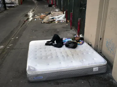 FILE - A homeless man sleeps on a discarded mattress in Los Angeles, July 21, 2022. Over the objections of homeless advocates, the Los Angeles City Council two years ago passed a broad anti-camping measure that was billed as a compassionate approach to get people off the streets and restore access to public spaces in the city with the nation's second-largest homeless population. (AP Photo/Jae C. Hong, File)