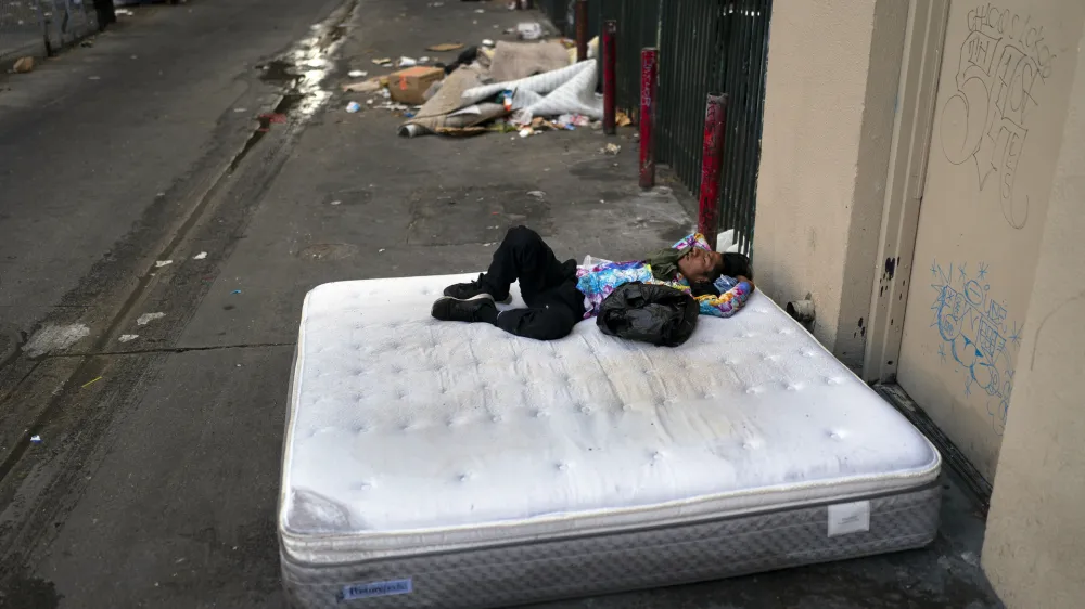 FILE - A homeless man sleeps on a discarded mattress in Los Angeles, July 21, 2022. Over the objections of homeless advocates, the Los Angeles City Council two years ago passed a broad anti-camping measure that was billed as a compassionate approach to get people off the streets and restore access to public spaces in the city with the nation's second-largest homeless population. (AP Photo/Jae C. Hong, File)