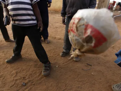 South African kids, using a ragged ball, one holding a toy weapon, play soccer in Thokoza, on the outskirts of Johannesburg, South Africa, Thursday, July 1, 2010. (AP Photo/Hassan Ammar)