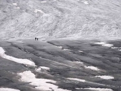 Team members of ETH (Swiss Federal Institute of Technology) glaciologist and head of the Swiss measurement network 'Glamos', Matthias Huss, arrive at the Rhone Glacier to take measurements near Goms, Switzerland, Friday, June 16, 2023. (AP Photo/Matthias Schrader)