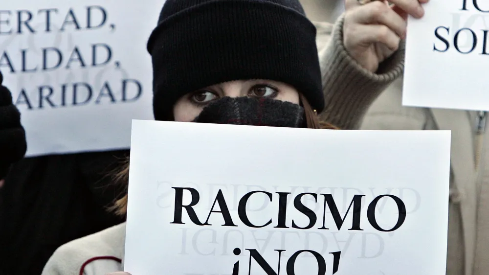 Demonstrators gather during an anti-racism protest in Alcorcon, a suburb of Madrid, Saturday Jan. 27, 2007, a week after a street battle between Spanish and immigrant gangs which ended with seven arrested and at least four injured. Minor street disturbances again took place Saturday evening with police continuously dispersing groups of stone throwing youths. Placard reads: 'Racism, No' (AP Photo/Paul White)