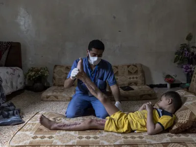 20 June 2023, Syria, Idlib: A medical volunteer from the Specialized Center for Rehabilitation and Physiotherapy follows up on the treatment of Mohammed Ghannam, 6 years old, who suffers from Crush Syndrome as a result of the earthquake. The medical team works to help and rehabilitate people with serious injuries such as amputation of limbs and crush syndrome in order to rely on themselves and receives 2000 cases per month. Photo: Anas Alkharboutli/dpa