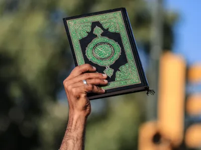 30 June 2023, Iraq, Baghdad: A man rises a copy of Islam's holy book, the Quran, during a protest against the burning a copy of the Quran in Sweden. Photo: Ameer Al-Mohammedawi/dpa