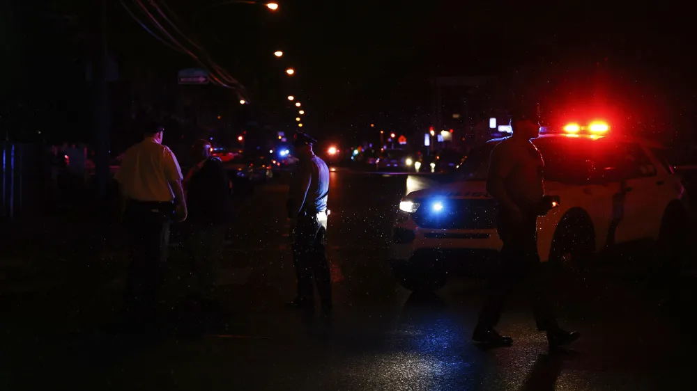 Philadelphia police stand at the intersection of 56th Street and Kingsessing Avenue after multiple people were shot in Southwest Philadelphia, late Monday, July 3, 2023. (Yong Kim/The Philadelphia Inquirer via AP)