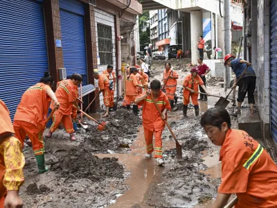 In this photo released by China's Xinhua News Agency, workers clean up silt and mud along a street in the Wanzhou district of Chongqing, China, Tuesday, July 4, 2023. More than a dozen people have been killed by floods in southwestern China as seasonal torrents hit mountain areas, authorities said Wednesday. (Ran Mengjun/Xinhua via AP)