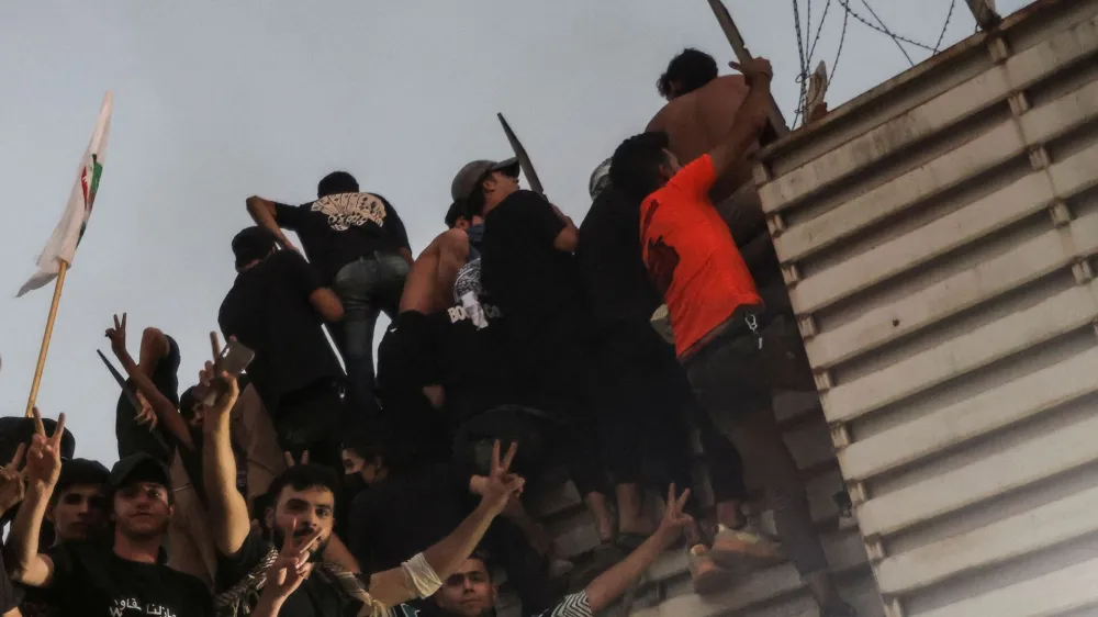 Protesters climb a fence as they gather near the Swedish embassy in Baghdad hours after the embassy was stormed and set on fire ahead of an expected Koran burning in Stockholm, in Baghdad, Iraq, July 20, 2023. REUTERS/Ahmed Saad   TPX IMAGES OF THE DAY