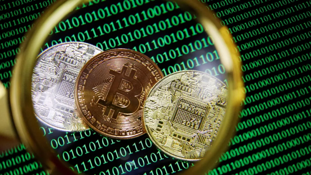 FILE PHOTO: Representations of Bitcoin and other cryptocurrencies on a screen showing binary codes are seen through a magnifying glass in this illustration picture taken September 27, 2021. REUTERS/Florence Lo/Illustration/File Photo