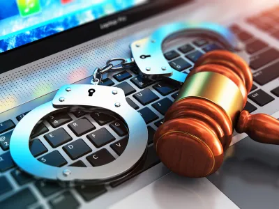 Creative abstract cyber crime, online piracy and internet web hacking concept: 3D render illustration of the macro view of metal handcuffs and wooden judge mallet, gavel or hammer on laptop notebook computer keyboard with selective focus effect