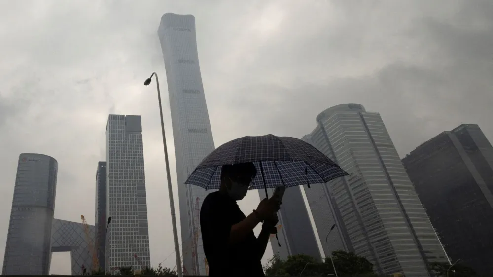 FILE PHOTO: A man walks in the Central Business District on a rainy day, in Beijing, China, July 12, 2023. REUTERS/Thomas Peter/File Photo