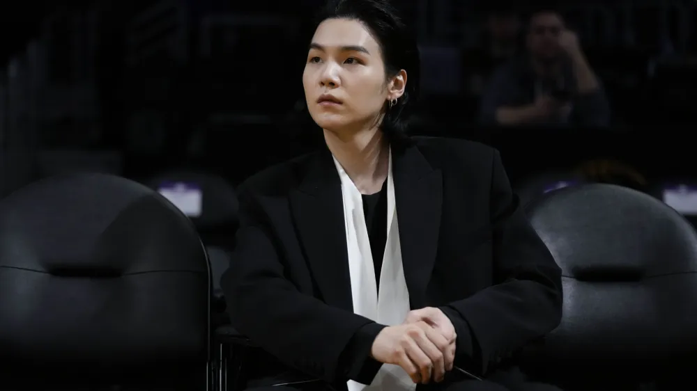 FILE - BTS member Suga attends an NBA basketball game between the Los Angeles Lakers and the Dallas Mavericks on Jan. 12, 2023, in Los Angeles. Suga has become the third member of BTS to begin South Korea's compulsory military service. BTS' label, Big Hit Music, said in a statement on Monday, Aug. 7, 2023, that Suga "has initiated the military enlistment process by applying for the termination of his enlistment postponement." (AP Photo/Jae C. Hong, File)