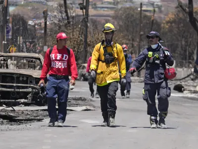 Members of a search and rescue team walk along a street on Saturday, Aug. 12, 2023, in Lahaina, Hawaii. (AP Photo/Rick Bowmer)