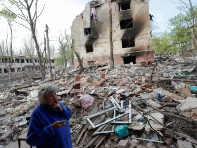 Local resident and nursery teacher Natalya Kalugina, 64, stands in a courtyard near a block of flats, which was destroyed during Ukraine-Russia conflict in the southern port city of Mariupol, Ukraine April 29, 2022. REUTERS/Alexander Ermochenko