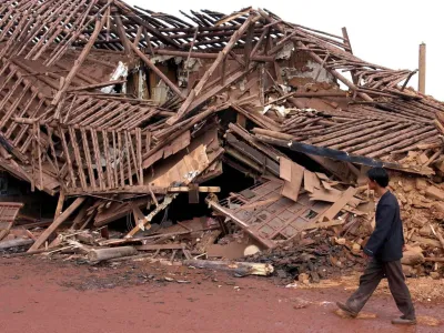 A man walks past a collapsed house following an earthquake measuring 6.2 on the Richter scale in Dayao County, southwest China's Yunnan Province, Tuesday, July 22, 2003. The quake has so far left 15 people dead and 294 others injured, China's Ministry of Civil Affairs said on Tuesday. (AP Photo/Xinhua,Wang Changshan)