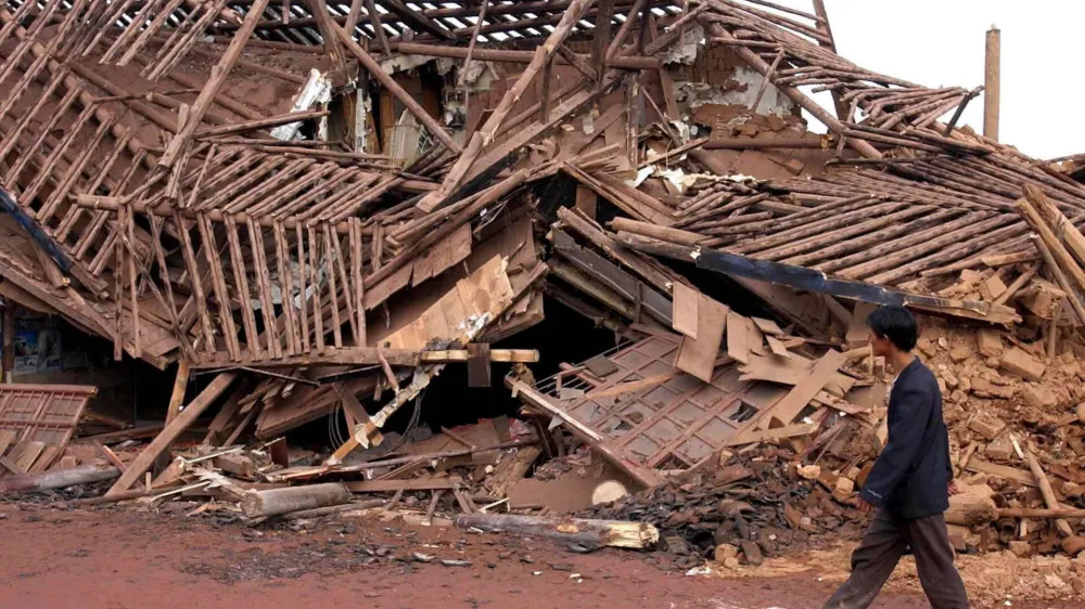 A man walks past a collapsed house following an earthquake measuring 6.2 on the Richter scale in Dayao County, southwest China's Yunnan Province, Tuesday, July 22, 2003. The quake has so far left 15 people dead and 294 others injured, China's Ministry of Civil Affairs said on Tuesday. (AP Photo/Xinhua,Wang Changshan)