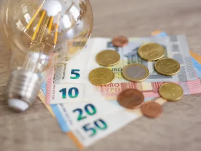 expensive energy bill and rise in electricity prices concept - light bulb with Euro banknotes and coins