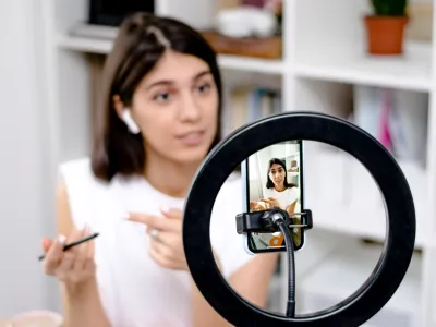 Influencer girl blogger talking smartphone,live recording video blog on social network at home.Social media live streaming concept.Focus on the phone, the girl in the background in a blur.