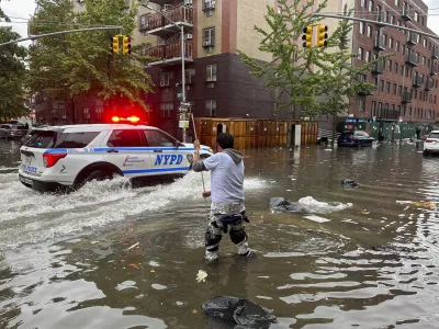 A man works to clear a drain in flood waters, Friday, Sept. 29, 2023, in the Brooklyn borough of New York. A potent rush-hour rainstorm has swamped the New York metropolitan area. The deluge Friday shut down swaths of the subway system, flooded some streets and highways, and cut off access to at least one terminal at LaGuardia Airport. (AP Photo/Jake Offenhartz)