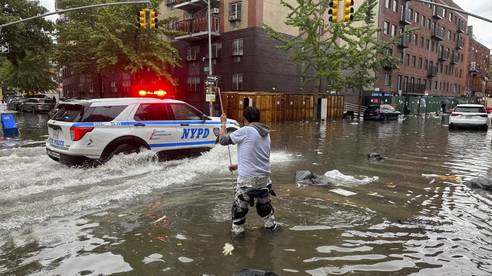 A man works to clear a drain in flood waters, Friday, Sept. 29, 2023, in the Brooklyn borough of New York. A potent rush-hour rainstorm has swamped the New York metropolitan area. The deluge Friday shut down swaths of the subway system, flooded some streets and highways, and cut off access to at least one terminal at LaGuardia Airport. (AP Photo/Jake Offenhartz)