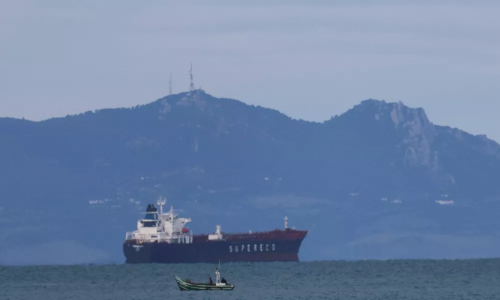 A Moroccan fisherman sails next to an oil tanker crossing the Strait of Gibraltar with the Atlas Mountains in the background, near the Spanish town of Tarifa, as seen from Tangier, Morocco, January 8, 2026. REUTERS/Amr Abdallah Dalsh