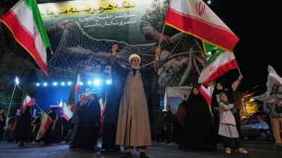 A Shiite cleric holds an Iranian flag during a pro-government gathering in a square in Tehran, Iran, Sunday, April 5, 2026. (AP Photo/Francisco Seco)
