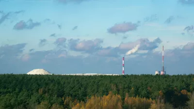 Industrial chemical plant in Gomel, Belarus. A large white mound of chemical waste rises behind a green forest, symbolizing pollution and the environmental impact of industry. / Foto: Viktoryia Malinava