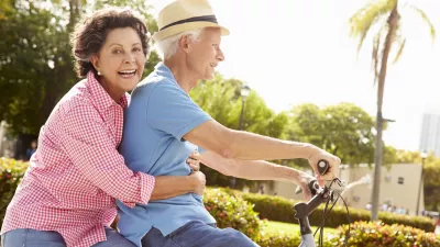 Senior Hispanic Couple Riding Bikes In Park Smiling To Camera