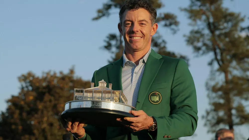 Golf - The Masters - Augusta National Golf Club, Augusta, Georgia, U.S. - April 12, 2026 Northern Ireland's Rory McIlroy celebrates with his green jacket and the trophy after winning The Masters REUTERS/Brian Snyder