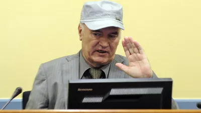 Former Bosnian Serb General Ratko Mladic salutes in the court room during his initial appearance at the U.N.'s Yugoslav war crimes tribunal in The Hague, Netherlands, Friday, June 3, 2011.Mladic's appearance Friday at the Yugoslav war crimes tribunal in The Hague is his first public appearance since he went into hiding nearly 16 years ago, when he was indicted for genocide and war crimes committed in the 1992-95 Bosnian war. (AP Photo/Martin Meissner, Pool)