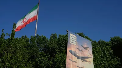 A banner shows a graphic depicting Iranian-built drones with a sign in Farsi that reads: "Arash drone is the nightmare for Iran's enemies," as an Iranian flag waves at left, in Tehran, Iran, Tuesday, April 21, 2026. (AP Photo/Vahid Salemi)