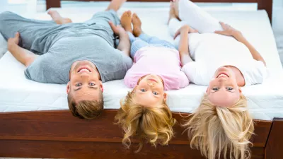 Photo of young family of three lying on nice white bed. Young family demonstrating quality of mattress