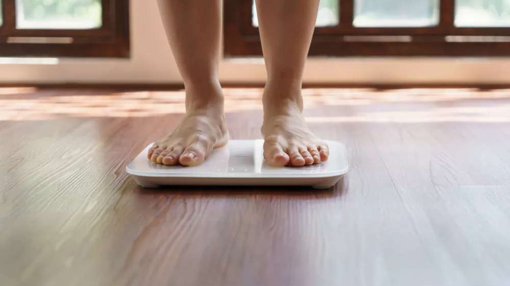 Fat diet and scale feet standing on electronic scales for weight control. Measurement instrument in kilogram for a diet control.